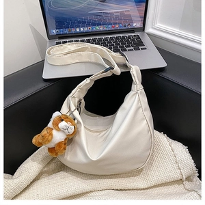 Detail view of cream white nylon crescent bag with cute tiger plush keychain accessory