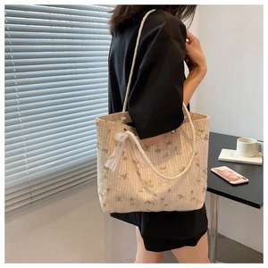 Détail du sac cabas en paille avec broderies florales et nœud en dentelle blanche