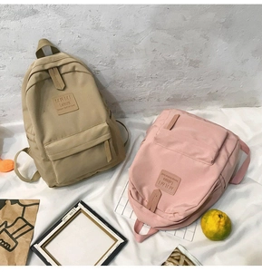 Detail view of khaki and pink casual nylon backpacks with front zip pockets
