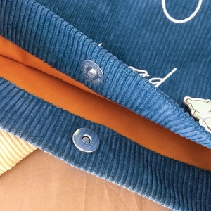 Détail du sac en velours côtelé sarcelle avec doublure orange et fermoir magnétique