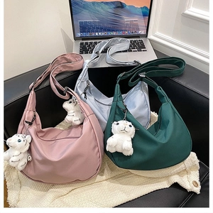 Detailed view of nylon crescent bags in pink, blue, and green with cute tiger charms