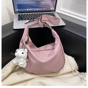 Pink nylon hobo bag featuring a cute white tiger plush charm in a cozy office setting