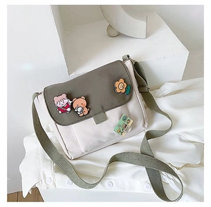 Détail du sac bandoulière en toile avec sangle vert olive et breloques d'ours mignons