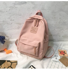 Close-up of a pink nylon backpack with multi-pocket design and brown leather label