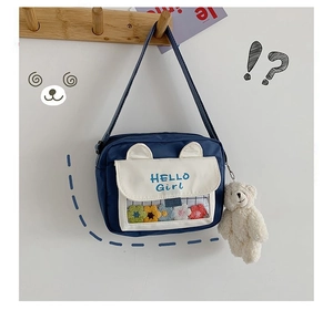 Detail of cute navy canvas crossbody bag featuring animal ears and a plush bear charm