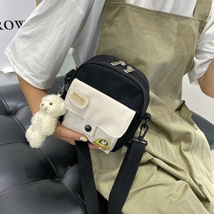 Detail view of mini nylon crossbody bag featuring cute bear charm and car patch accessory