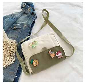 Détail d'un petit sac en toile avec des badges mignons et une bandoulière vert olive