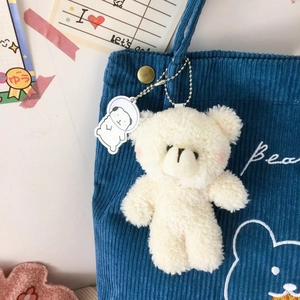 Gros plan d'un pendentif ours en peluche et astronaute sur un sac en velours bleu