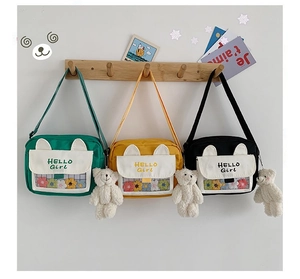 Detailed view of canvas crossbody bags in three colors with plush bear charm