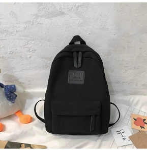 Close-up of black canvas backpack with grey leather patch and durable front zipper pocket