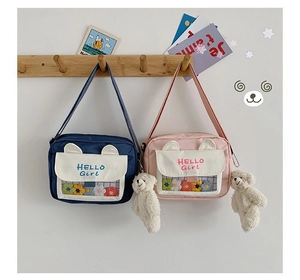 Close-up of cute crossbody bag featuring a transparent pocket and plush bear charm