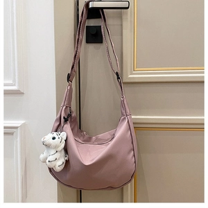 Pink nylon crescent crossbody bag detail with cute white tiger plush charm on a handle