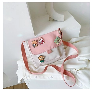 Détail du sac bandoulière en toile rose et blanc avec broches d'ours de dessin animé