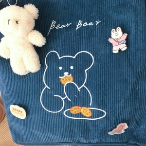 Détails de la sacoche en velours côtelé bleu avec broderie ours et écussons