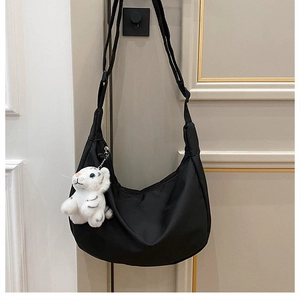 Detail of black nylon crescent hobo bag featuring a cute white plush tiger keychain accessory