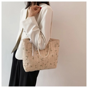 Détail d'un sac cabas en paille avec broderies florales et anse en corde de coton