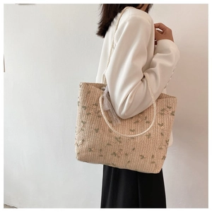 Détail du sac cabas en paille d'été avec broderie fine de vigne et fleurs roses