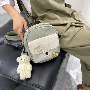 Close-up of canvas mini bag with cartoon car patch and cute white plush bear keychain