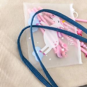 Gros plan d'une pochette givrée avec stylos licorne sur fond en velours côtelé