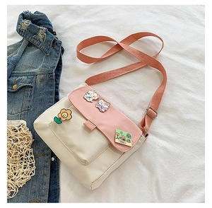 Détail d'un petit sac bandoulière en toile avec badges ours et bandoulière rose réglable