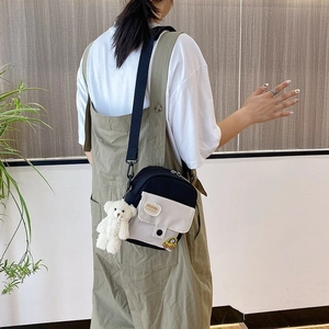 Detailed view of mini nylon crossbody bag featuring bread patch and plush bear pendant