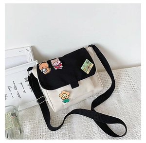Détail du sac bandoulière en toile avec des épingles d'ours mignons et un badge fleuri