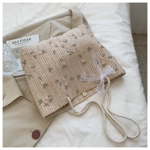 Détail du sac cabas en paille tissé à la main avec broderie florale et nœud en dentelle