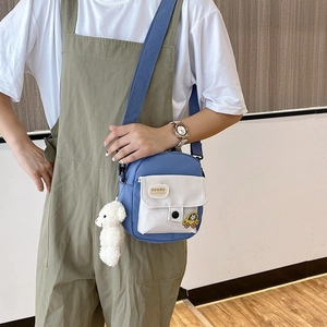 Detail of nylon crossbody bag with cloud embroidery, cartoon badge and plush bear charm