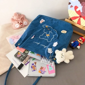 Vue détaillée du sac fourre-tout en velours bleu avec intérieur spacieux et breloque d'ours
