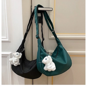 Detail of nylon crescent bags with plush tiger charms and adjustable straps