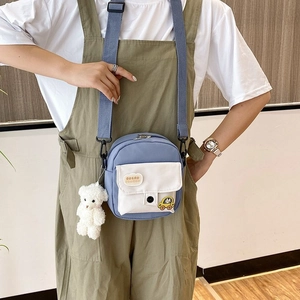 Close-up of small nylon canvas crossbody bag featuring a cute bear pendant and cloud patch
