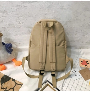 Detail of adjustable shoulder straps and top handle on a khaki nylon backpack