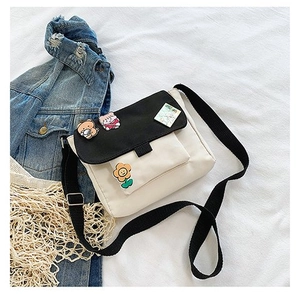Vue à plat du sac bandoulière en toile avec badges de dessin animé et large sangle