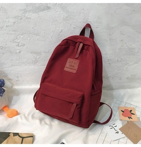 Close-up of wine red nylon backpack with fabric handle and front zipper pocket