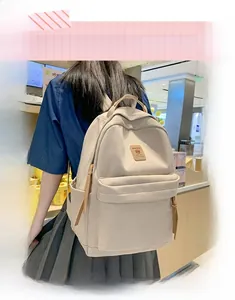 Detail view of a minimalist beige nylon backpack featuring large main compartment and front pocket