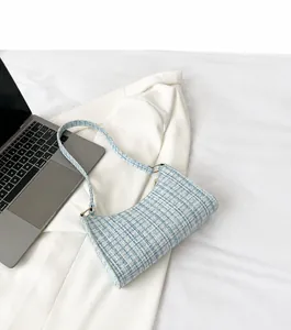 Blue and white tweed shoulder bag displayed with a white blazer and laptop for work