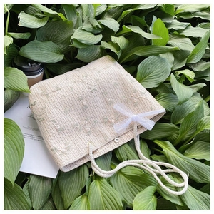 Détail du sac cabas beige tressé avec broderie florale et nœud en dentelle délicat