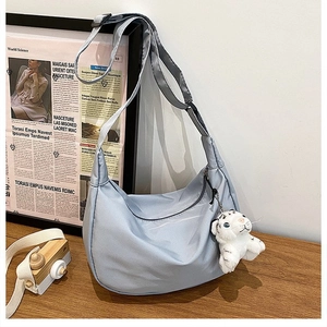 Detail of light blue nylon crescent bag with adjustable strap and cute tiger plush charm
