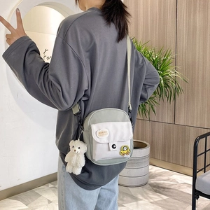 Close-up of nylon mini crossbody bag with cute cloud tag and white plush bear pendant