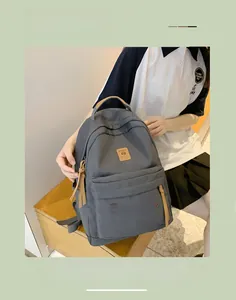 Detail view of a grey nylon backpack with large main pocket and brown leather zip pullers