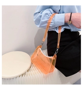 Close-up of orange transparent jelly bag with silver metal zipper and shoulder strap hook