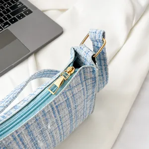 Detail of blue and white tweed shoulder bag with a smooth golden metal zipper closure