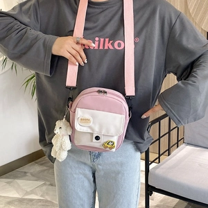Detailed view of pink nylon mini crossbody bag with cartoon cloud patch and plush charm