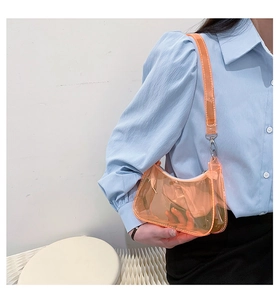 Detail of transparent orange PVC shoulder bag featuring silver metal connectors on the strap