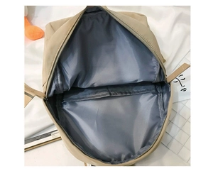 Detail view of the spacious inner compartment and laptop sleeve of this minimalist beige backpack