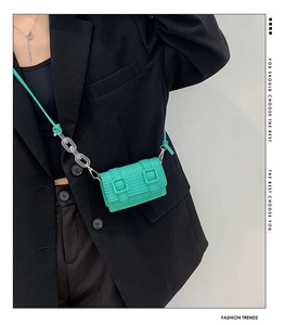 Détail d'un mini sac bandoulière vert fluo avec texture tissée et chaîne acrylique