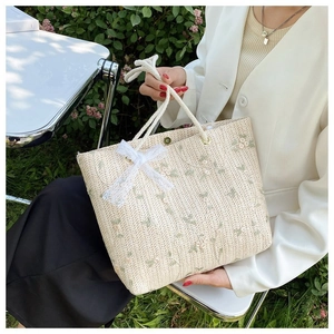 Détail du sac cabas tissé avec broderie florale, nœud en dentelle et poignée en corde