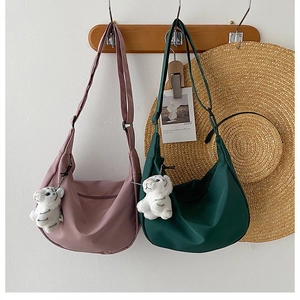 Detail of pink and green nylon crescent bags with plush tiger charms on wooden hooks