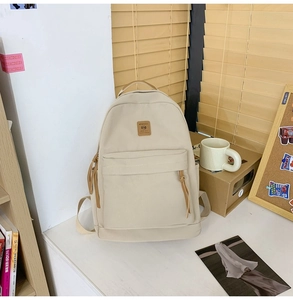 Close-up of cream white nylon backpack with water bottle side pocket and leather zip puller