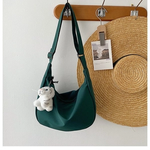 Detail of dark green crescent nylon bag with adjustable strap and small tiger charm